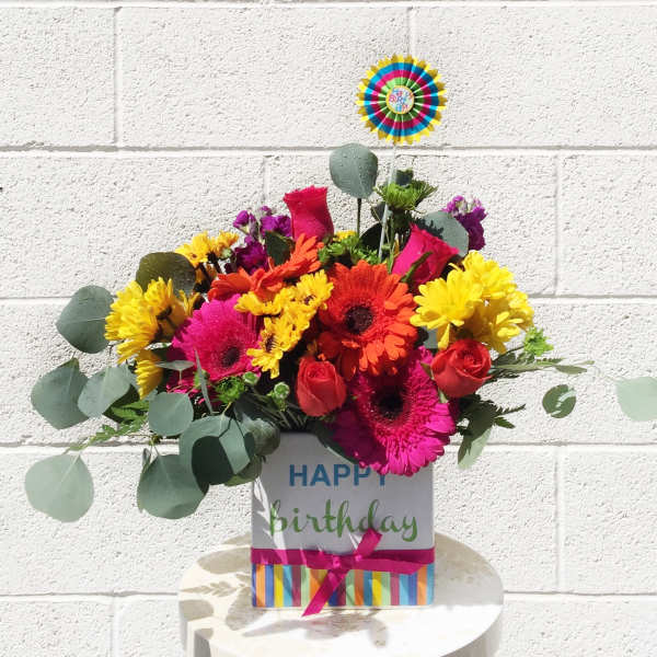 Birthday flower arrangement in a decorated gift box with a topper