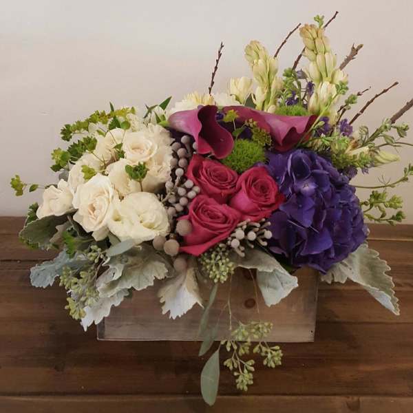 Mixed bouquet with white, pink, and purple flowers in a wooden box