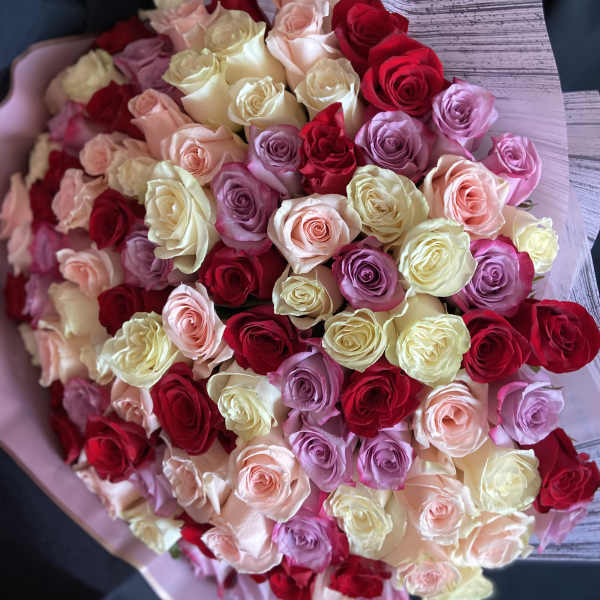 Large bouquet of red, pink, and cream roses wrapped in pale paper