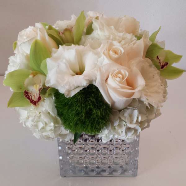 White and pale peach floral arrangement in a clear textured vase