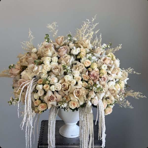 Large cream and blush rose arrangement in a white urn vase