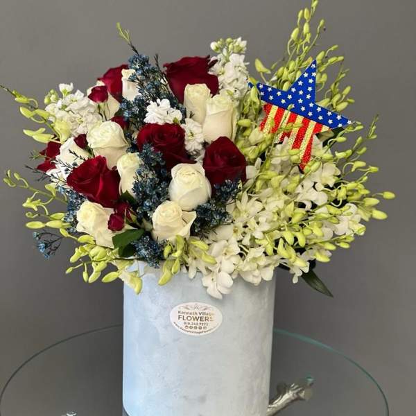 Red and white roses in a white hat box with a patriotic star decoration.