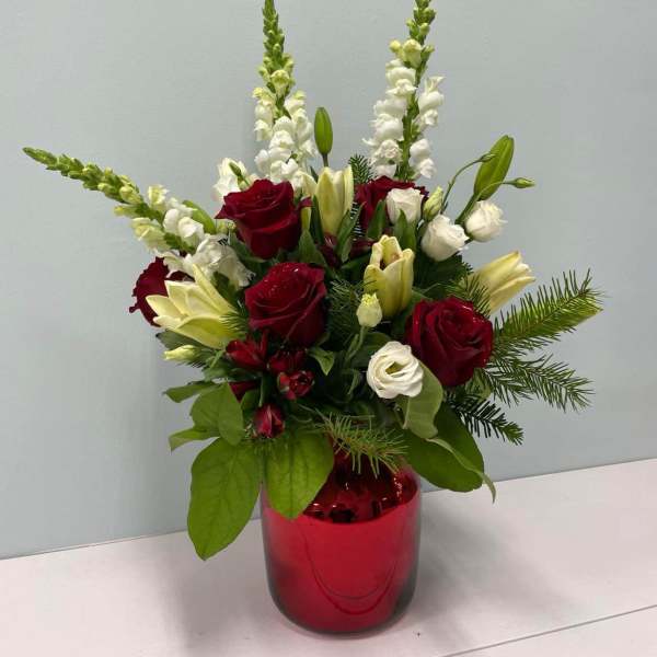 Red and white floral arrangement in a red glass vase