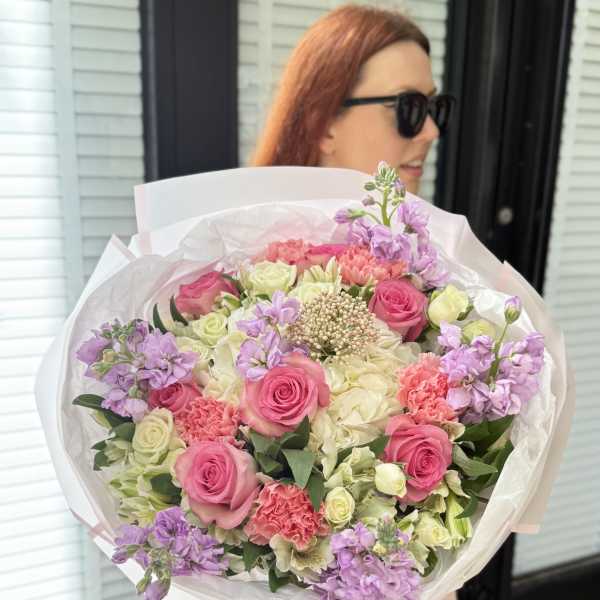 Large bouquet of pink and cream roses with lavender flowers in white wrap