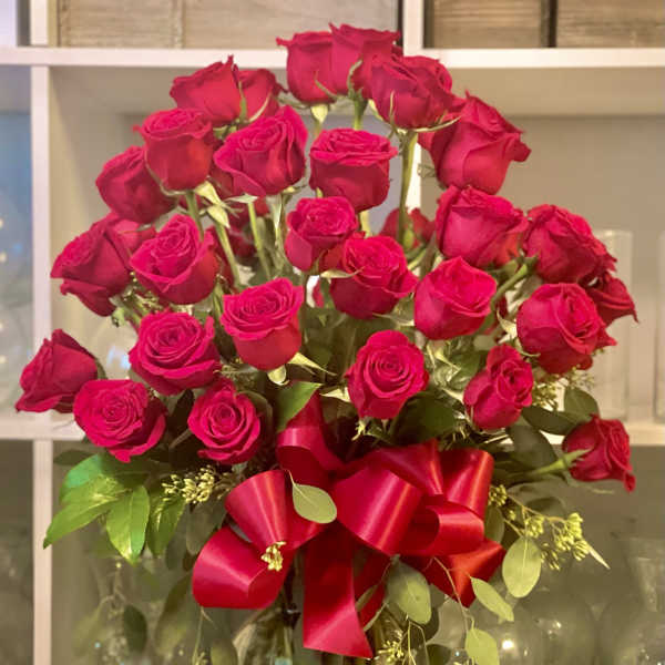 Bouquet of red roses in a glass vase with a red ribbon