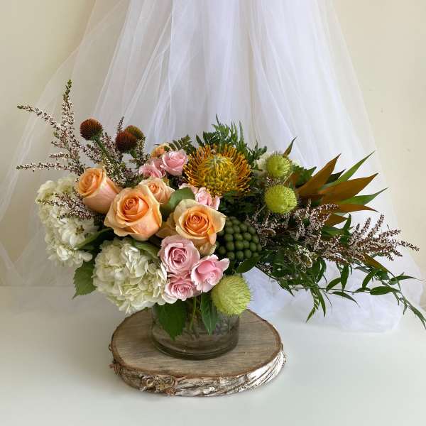 Mixed bouquet of peach and pink roses in a glass vase