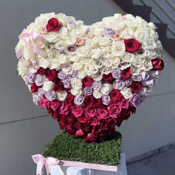 Heart-shaped rose arrangement in white, pink, and red with a pink ribbon