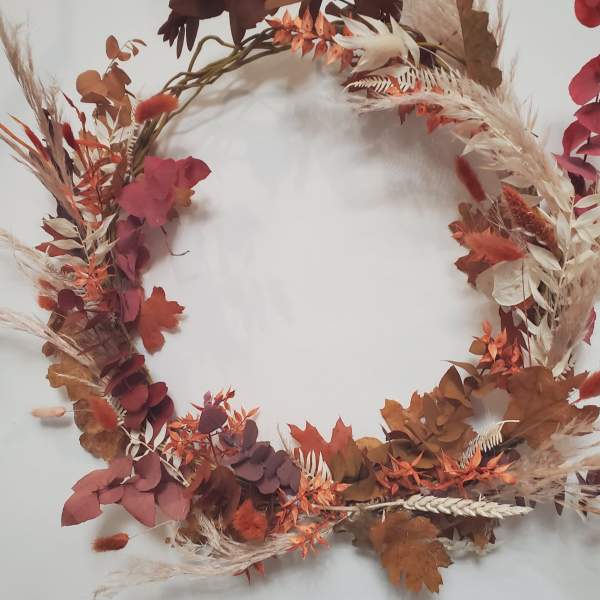 Autumn wreath with dried leaves and grasses in rust and burgundy tones