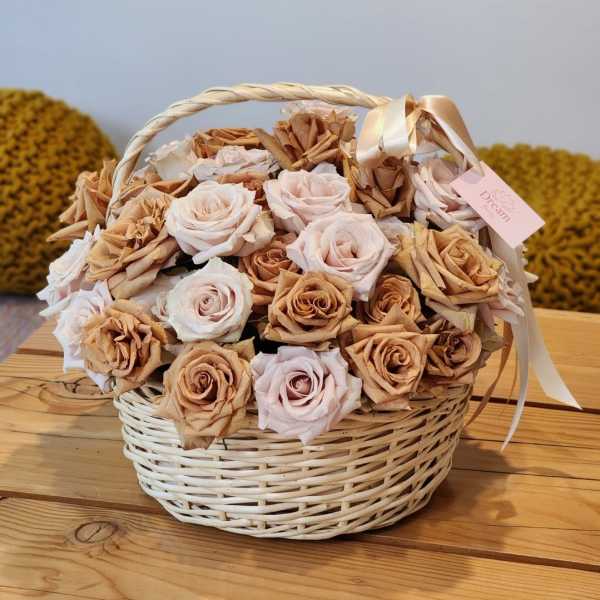 Basket of pale roses and dried tan flowers with a ribbon
