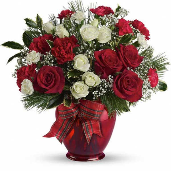 Red and white roses arranged in a red vase with a plaid ribbon