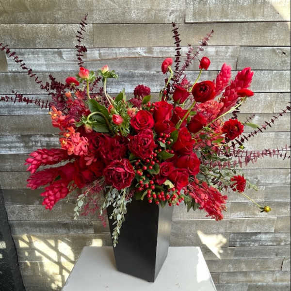 Large red floral arrangement in a tall black vase