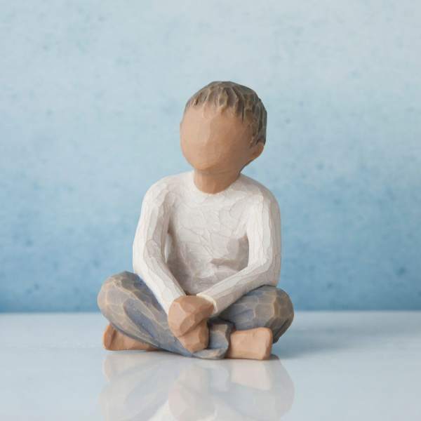 Small faceless seated figurine with a white shirt and blue pants