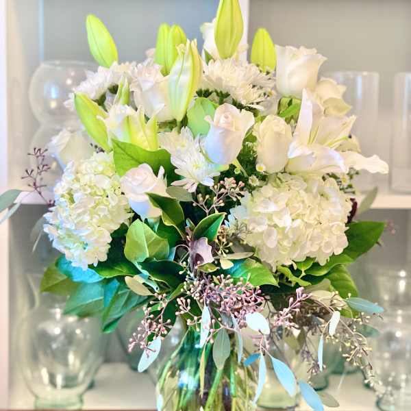 White lilies and roses arranged in a glass vase
