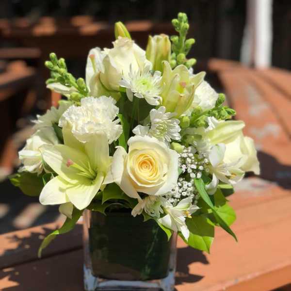 White floral arrangement in a square glass vase