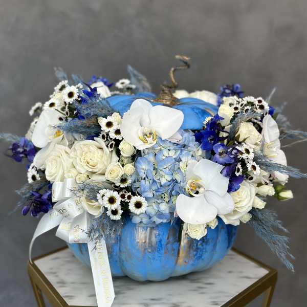 Blue pumpkin-shaped arrangement with white orchids, roses, and small daisies
