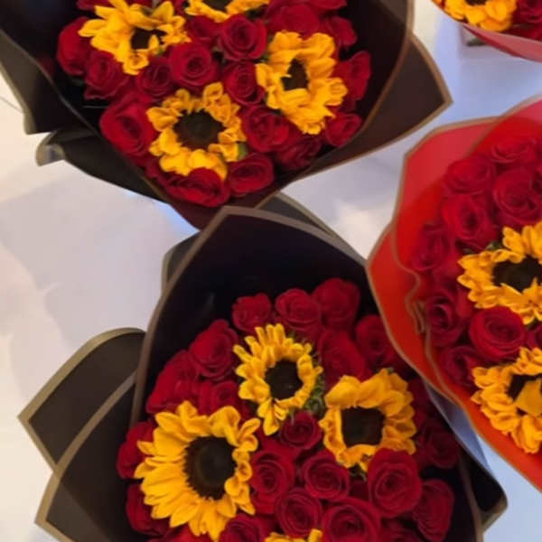 Bouquets of red roses and yellow sunflowers in dark wrapping