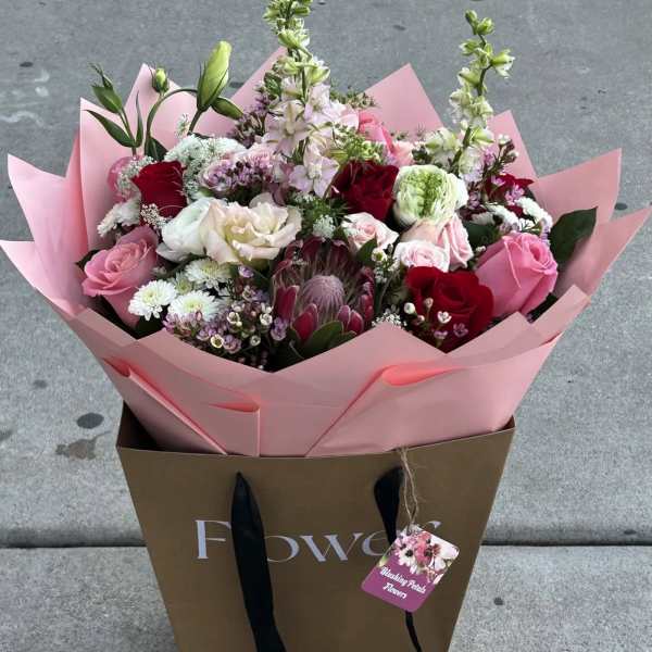 Mixed bouquet of pink, red, and white flowers in pink wrap