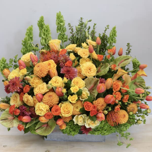 Large orange and yellow floral arrangement in a rectangular container