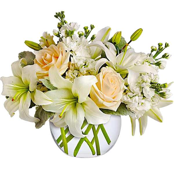 White lilies and pale peach roses in a clear glass vase