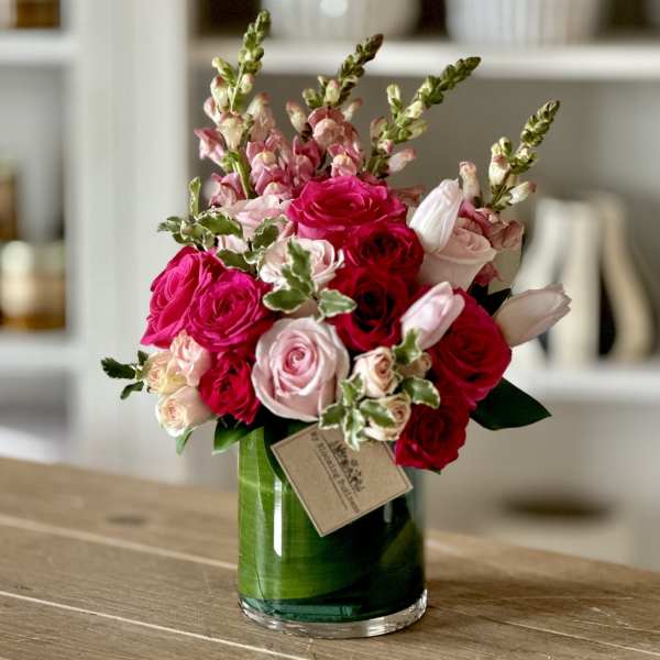 Pink and red rose bouquet in a green glass vase