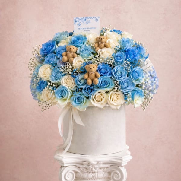 Blue and white rose arrangement in a white hat box with small teddy bears