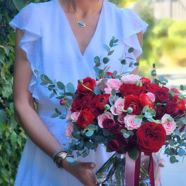 Woman holding a bouquet of red and pink roses in a glass vase