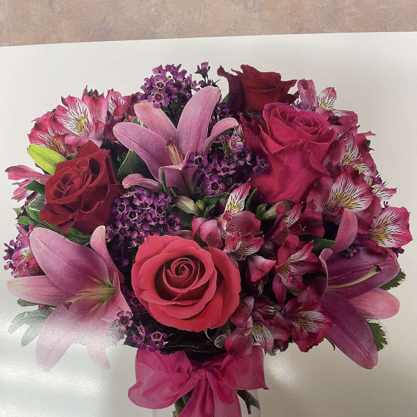 Pink and red bouquet of roses and lilies in a clear glass vase