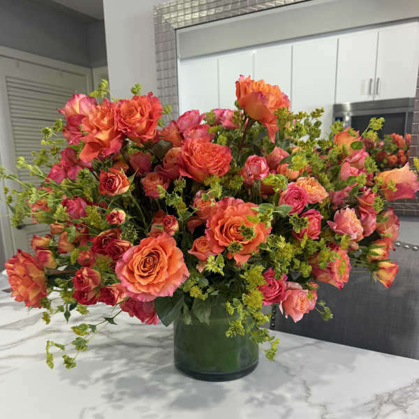 Large bouquet of orange and pink roses in a glass vase