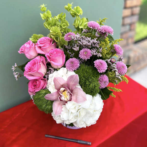 Pink roses and white hydrangeas with a pink orchid in a vase