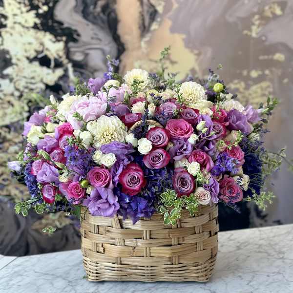 Mixed pink, purple, and white flowers in a woven basket