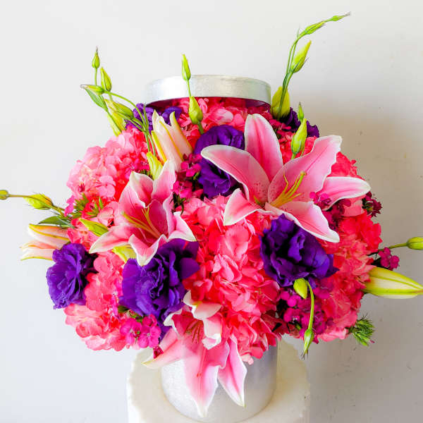 Pink lilies and purple flowers in a silver hatbox