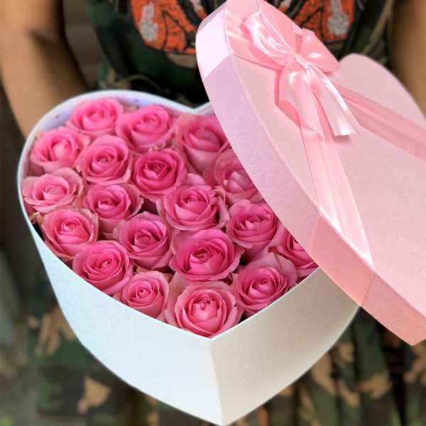 Heart-shaped box filled with pink roses and a pink ribbon lid