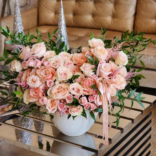 Large bouquet of pale pink roses in a white vase with silver cone accents