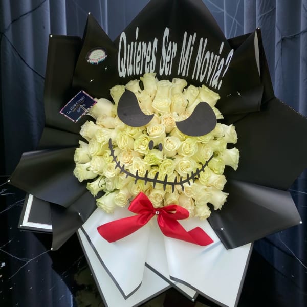 Bouquet of cream roses wrapped in black paper with a red bow and face cutout