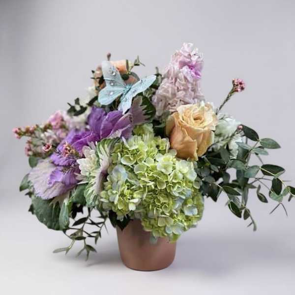 Bouquet of pastel flowers in a terracotta vase with a butterfly decoration