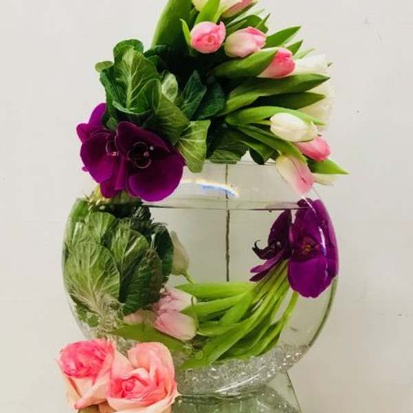 Pink and white tulips with purple orchids in a glass vase