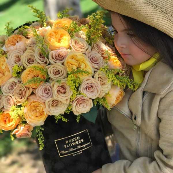 Large bouquet of peach and cream roses in a black box