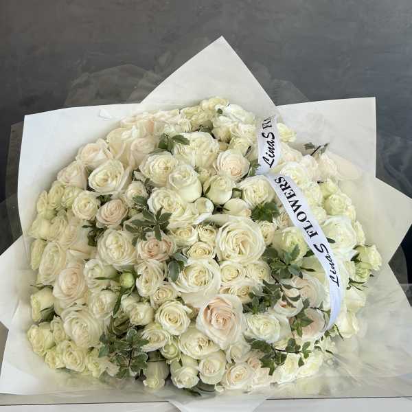 Large bouquet of white roses wrapped in white paper