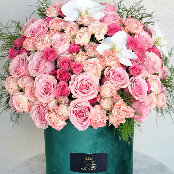 Pink roses and carnations in a green velvet box with white orchids
