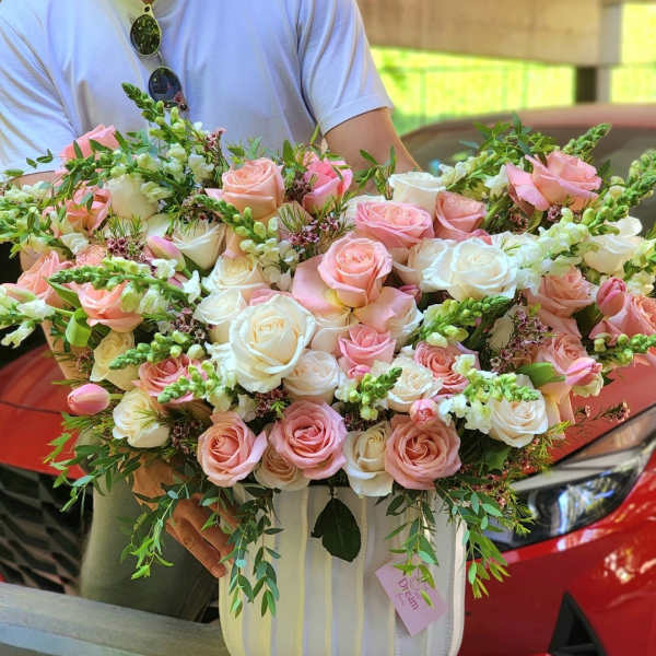 Large bouquet of pink and white roses in a striped box