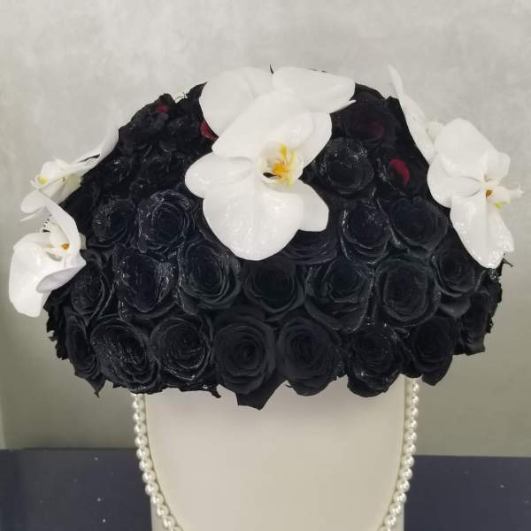 Black rose arrangement with white orchids in a white vase