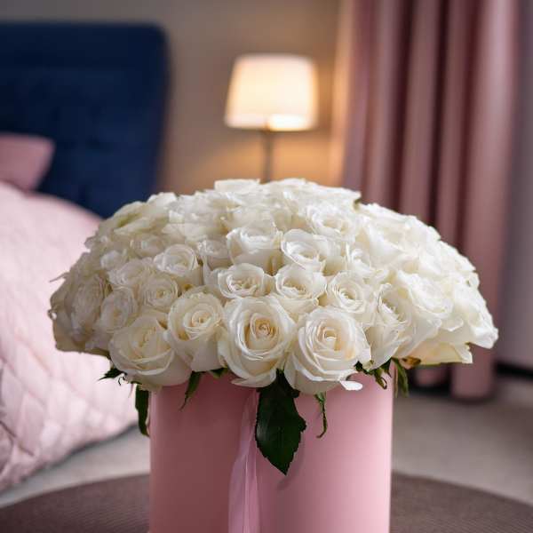 White roses arranged in a pink round box