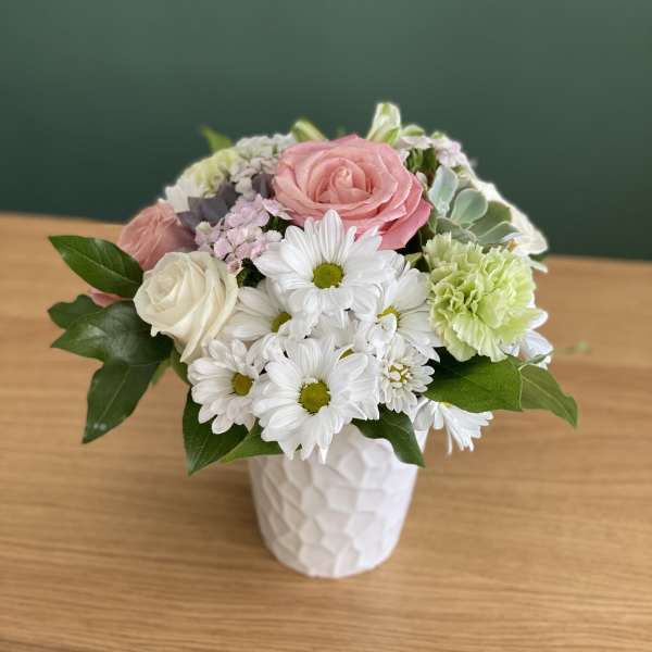 Pink and white flowers arranged in a white vase