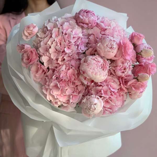 Bouquet of pink peonies and hydrangeas wrapped in white paper