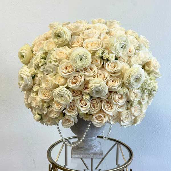 Cream rose and ranunculus arrangement in a gray urn vase