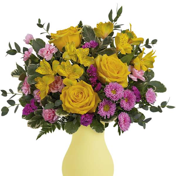 Yellow roses and pink flowers in a pale yellow vase