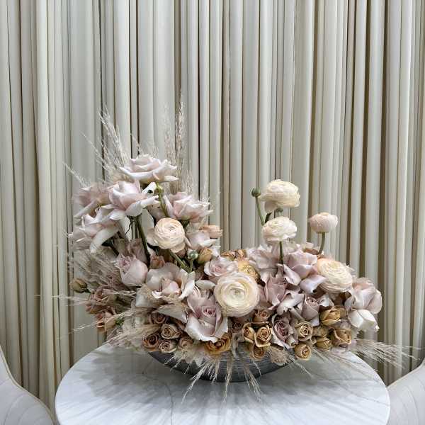 Large pastel floral arrangement in a low bowl on a round table