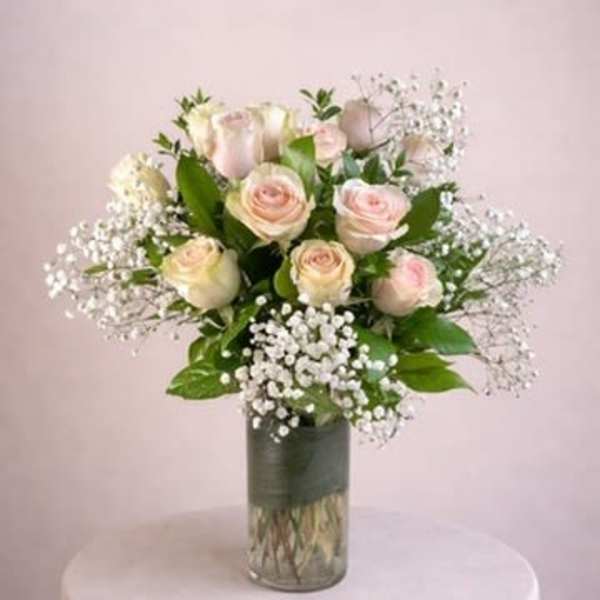 Bouquet of pale pink roses and baby's breath in a glass vase