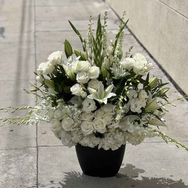 White roses and lilies arranged in a black vase