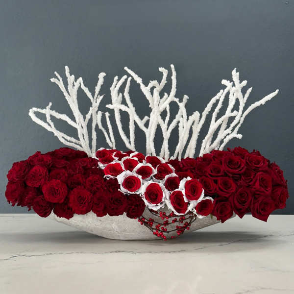 Low arrangement of red roses with white accents in a shallow bowl